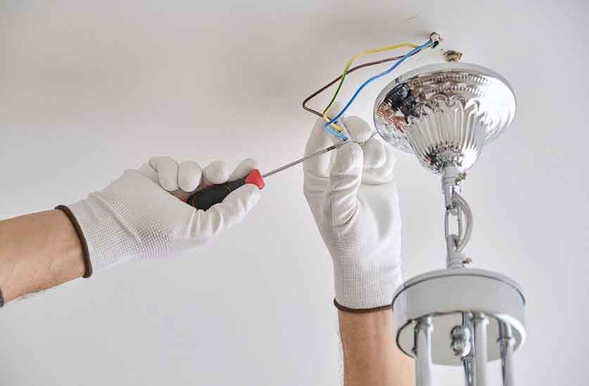 Installation ceiling lamp lighting, hands of male electrician fixing chandelier with use of professional tools