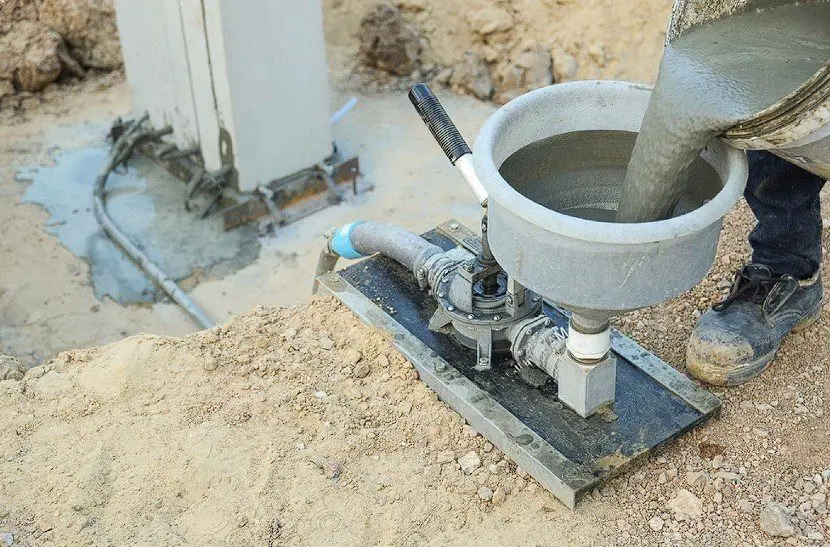 Specialist using machine grout pressure pump for grouting non-shrink concrete to precast column