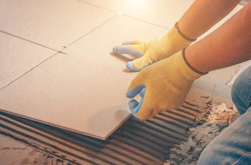 hands of worker laying floor ceramic tiles