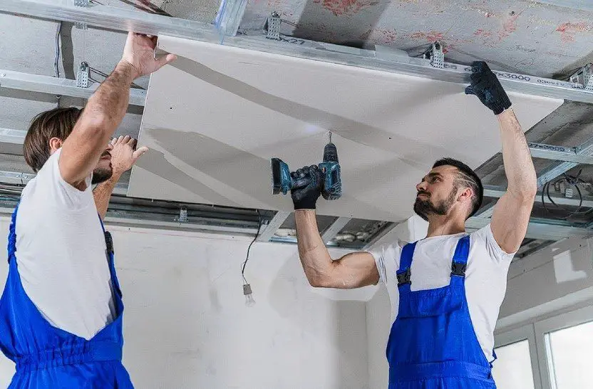 two workers installing suspended ceiling covers